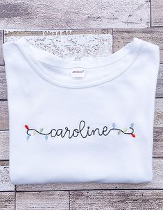 a white t - shirt with the word caroline on it sitting on top of a wooden floor