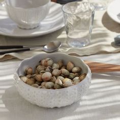 a bowl filled with shells sitting on top of a table next to plates and utensils