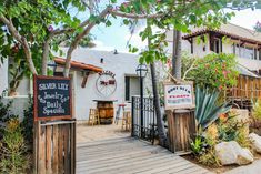 the outside of a restaurant with signage on it's front door and wooden deck