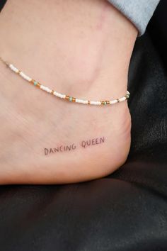 a woman's foot with the words dancing queen written on it and a beaded ankle bracelet