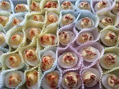 several trays filled with deviled eggs on top of each other and topped with toppings