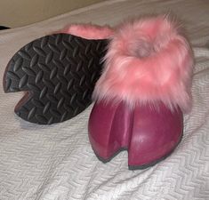 two pairs of shoes with pink fur lined up on a bed