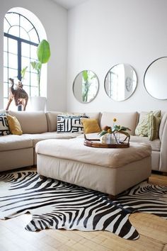 a living room with zebra print rugs and round mirrors on the wall above the couch