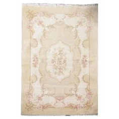 an antique rug with floral designs and fringes on the bottom, in cream tones