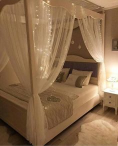 a bed with white curtains and lights on it