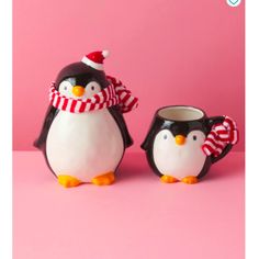 two penguins wearing hats and scarfs are standing next to each other on a pink surface