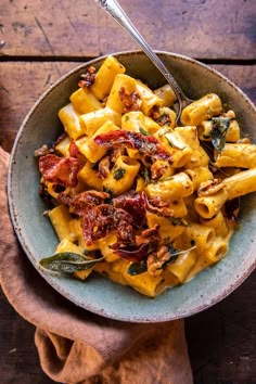 a bowl filled with pasta and spinach on top of a wooden table