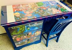 a blue desk with avengers comic covers on it and two chairs next to the desk