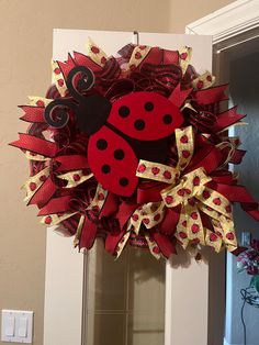 a red and yellow ladybug wreath hanging on the front door for someone's house