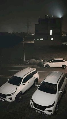 three cars parked in a parking lot at night