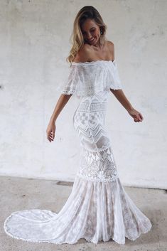 a woman in a white dress is posing for the camera with her hand on her hip