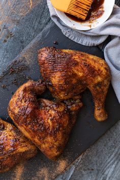 two pieces of chicken sitting on top of a cutting board next to a bowl of bbq sauce