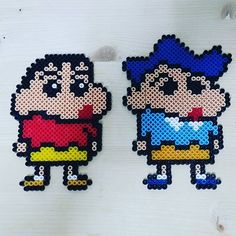 two cross stitch cartoon characters on white wood