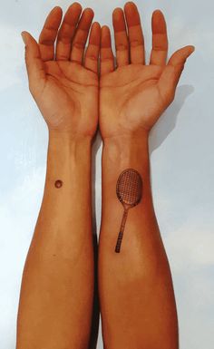 two hands with tattoos holding a tennis racket