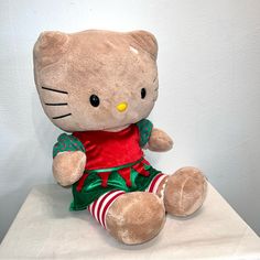 a hello kitty stuffed animal sitting on top of a white table next to a wall