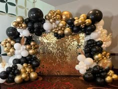 black, gold and white balloons are arranged on a table