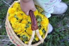 a doll holding a basket full of yellow dandelions in it's hands