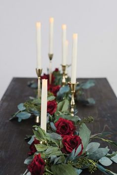 a long table with candles and red roses on it is set up for a formal dinner