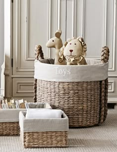 two stuffed animals sitting in a basket on the floor next to some books and pillows