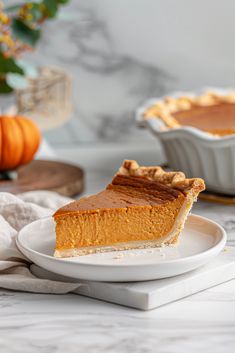 a slice of pumpkin pie on a white plate next to a bowl of pumpkins