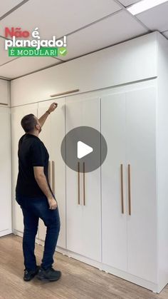 a man is standing in front of some closets and pointing to the wall with his hand