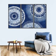 two blue paintings hanging on the wall in a living room with a couch and coffee table