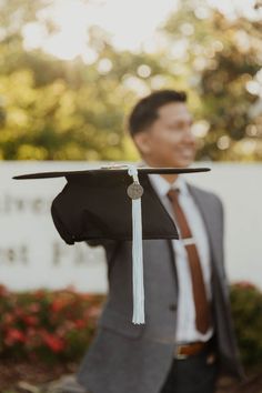 a man in a suit and tie holding a graduation cap with a tassel on it