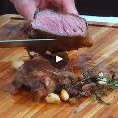 a person cutting meat on top of a wooden cutting board