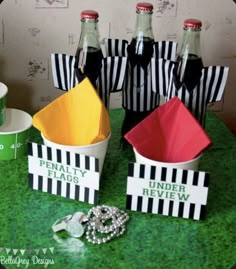 three empty soda bottles sitting on top of a green table next to candy boxes and other items