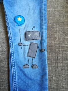 a pair of blue jeans with a robot drawn on the side and a balloon attached to it