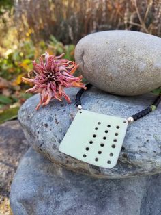 a necklace with a flower sitting on top of a rock