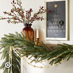 a christmas mantle decorated with pine branches and candles