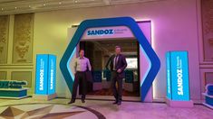 two men standing in front of an entrance to sandozz's new office