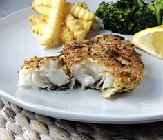 a white plate topped with fish and broccoli next to lemon wedges on a woven place mat