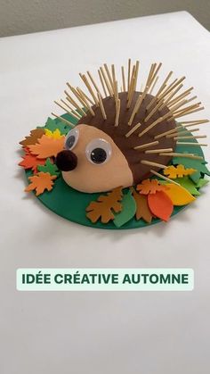 a hedgehog made out of paper sitting on top of a white table with leaves