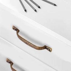 an image of drawer handles with pencils on it and white drawers in the background