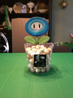 a vase filled with lots of white and blue candies on top of a green table