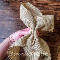 someone is holding a burlap bow on a wooden table