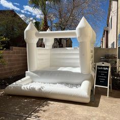 an inflatable bed sits on the sidewalk next to a sign and palm tree