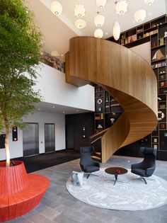 a spiral staircase in the middle of a living room with black chairs and bookshelves