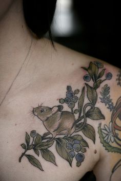 a woman with tattoos on her chest has a rat in the leaves and flowers tattoo