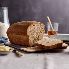 a loaf of bread sitting on top of a cutting board next to butter and honey