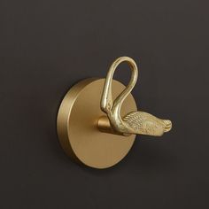 a brass swan hook on a black wall