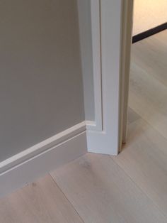 an open door in a room with hard wood flooring and white trim on the walls