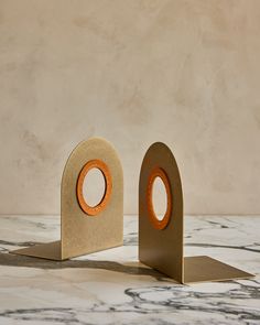 two pieces of cardboard with holes in the middle on a marble counter top, one has an orange circle at the center