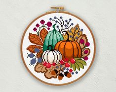 a cross stitch pattern with an autumn scene in the center and leaves, flowers, pumpkins and acorns on it