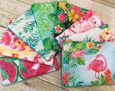 four flamingos, watermelon, and pineapple printed napkins on a wooden table