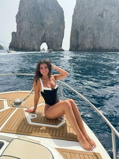 a woman sitting on the back of a boat in front of two large rock formations