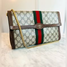 Authenticated Gucci Sherryline Clutch Bag. Front Flap With Fastener. Gg Monogram Coated Canvas With Sherryline Webbing. Comes With An Unbranded Gucci Style Strap Or A Long Gold Chain If You Prefer. Can Be Customized With D Rings To Add Strap Or A Chain Of Your Choice. This Bag Has A Very Practical Size Of 11.5” X 7.5” And Is In Excellent Vintage Condition. The Pouch Can Use As Clutch Or Easily Converted Into A Crossbody Bag. Clean, It Has A Ointment Smell Possibly Peppermint. Made In Italy. Reasonable Offers Only Questions? Leave A Comment Below! Gucci Clutch Bag, Gucci Clutch, Gucci Style, Gg Monogram, Vintage Clutch, Gucci Fashion, Clutch Pouch, Gucci Bags, The Pouch