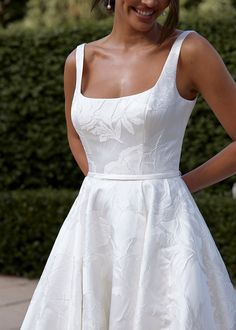 a woman in a white dress is smiling at the camera